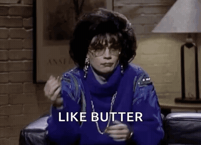 A Woman In A Blue Sweater Is Sitting On A Couch Eating A Piece Of Butter . GIF