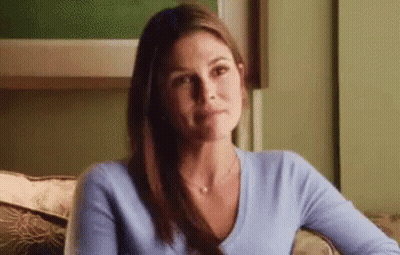 A Woman In A Blue Sweater Is Sitting On A Couch . GIF