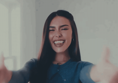 A Woman In A Blue Sweater Is Smiling And Giving A Thumbs Up GIF