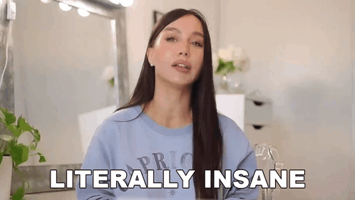 A Woman In A Blue Sweater Is Standing In Front Of A Mirror And Saying Literally Insane . GIF