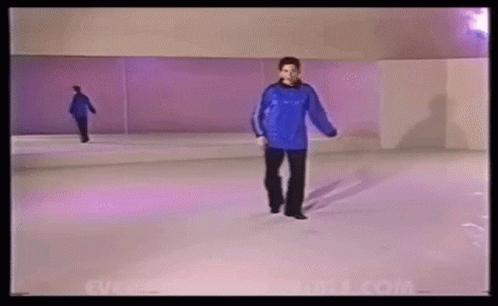 A Woman In A Blue Sweater Is Walking On A White Ice Rink . GIF