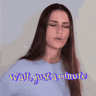 A Woman In A Blue Sweater Says Wait Just A Minute In Purple Letters GIF