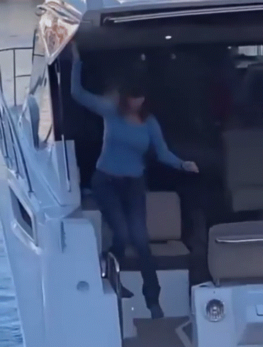 A Woman In A Blue Sweater Stands On A Boat GIF