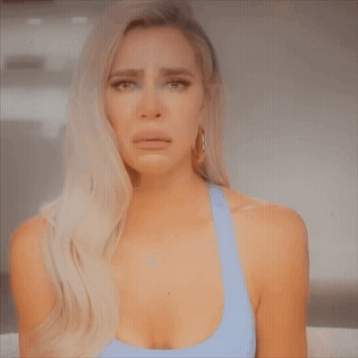 A Woman In A Blue Tank Top Is Crying And Making A Face . GIF