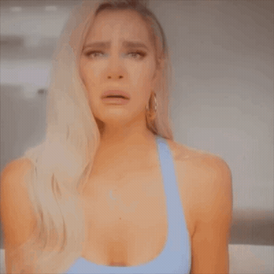 A Woman In A Blue Tank Top Is Crying . GIF