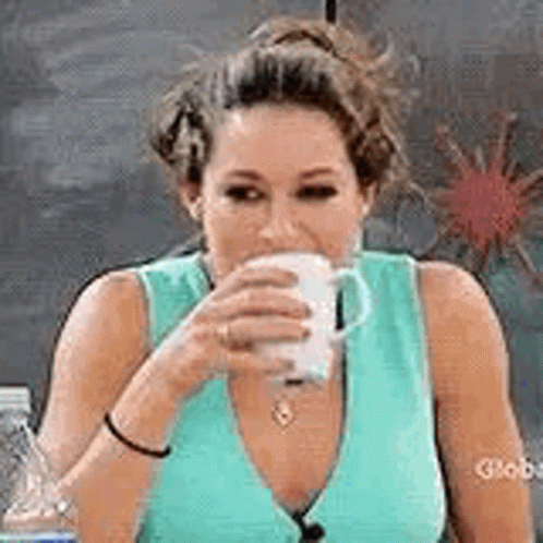 A Woman In A Blue Tank Top Is Drinking From A Cup . GIF
