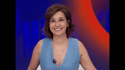A Woman In A Blue Tank Top Is Smiling And Wearing A Microphone . GIF
