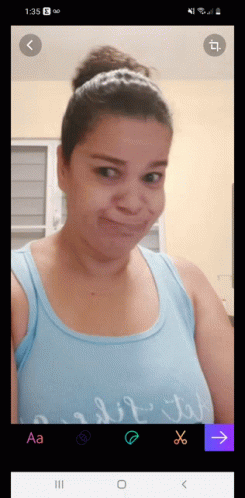 A Woman In A Blue Tank Top Is Taking A Picture Of Herself GIF