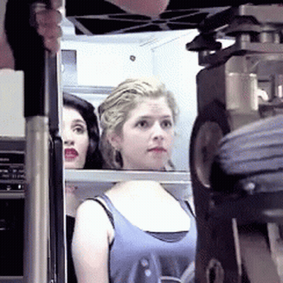 A Woman In A Blue Tank Top Looks At Something GIF