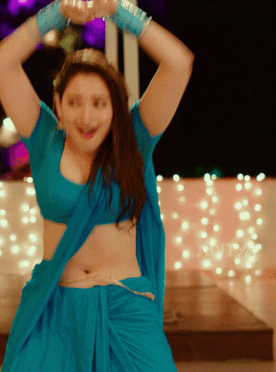 A Woman In A Blue Top And Skirt Is Dancing With Her Arms In The Air GIF