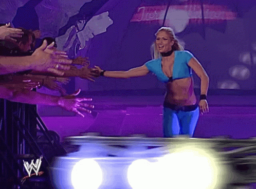 A Woman In A Blue Top Is Standing In Front Of A Crowd With A W On The Bottom GIF