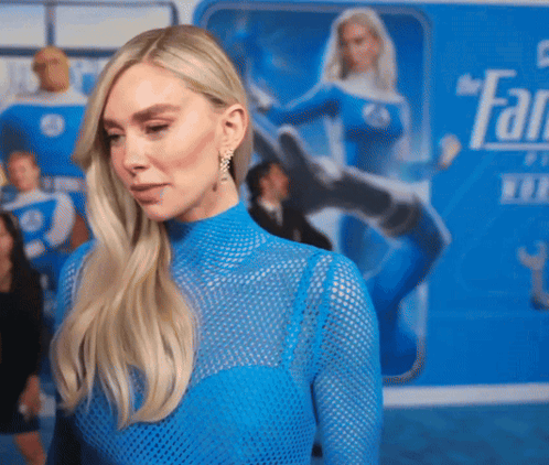 A Woman In A Blue Top Is Standing In Front Of A Sign That Says " Fantastic Four " GIF