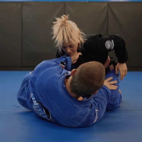 A Woman In A Blue Uniform With The Word Limit On The Back Is Wrestling A Man GIF