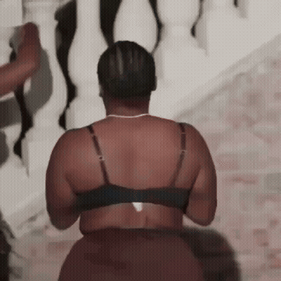 A Woman In A Bra And Skirt Is Standing In Front Of A White Railing . GIF