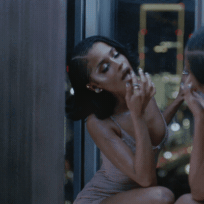 A Woman In A Braided Hairstyle Is Looking At Herself In The Mirror GIF