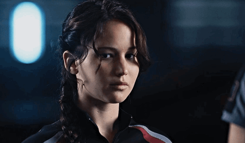A Woman In A Braided Ponytail Looks At The Camera GIF