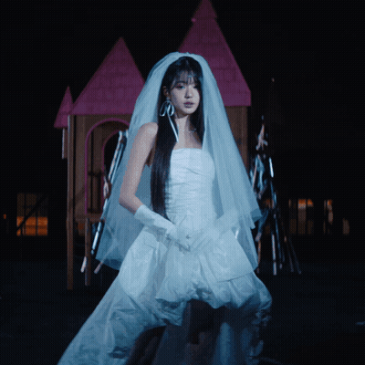 A Woman In A Bride 'S Dress Is Standing In Front Of A Fire GIF