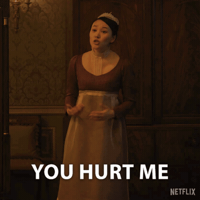 A Woman In A Brown Dress Is Standing In Front Of A Sign That Says You Hurt Me GIF