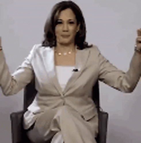 A Woman In A Business Suit Is Sitting In A Chair With Her Arms Outstretched . GIF