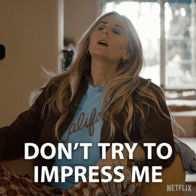 A Woman In A California Shirt Is Sitting In A Chair And Says Don 'T Try To Impress Me Netflix GIF