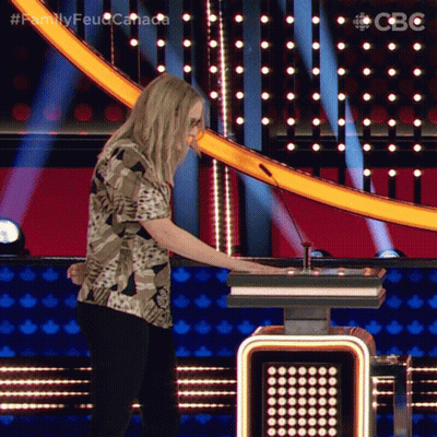 A Woman In A Camo Shirt Is Playing A Game On A Stage With The Words Family Feud Canada On The Bottom GIF