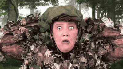 A Woman In A Camouflage Outfit Has A Surprised Look On Her Face . GIF