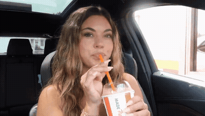 A Woman In A Car Drinking Through A Straw From A Cup That Says Made GIF