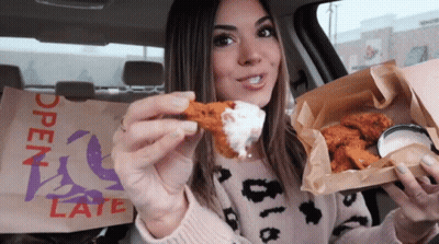 A Woman In A Car Eating Chicken Wings With A Bag That Says Open Late On It GIF