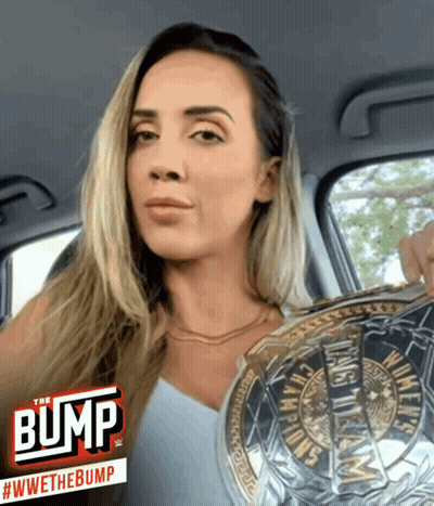 A Woman In A Car Holding A Wrestling Championship Belt With The Bump Logo In The Corner GIF