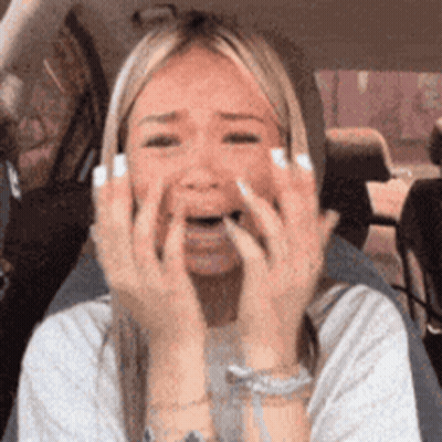 A Woman In A Car Is Covering Her Face With Her Hands GIF