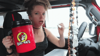 A Woman In A Car Is Holding A Red Mug That Says Buc-Ees On It GIF