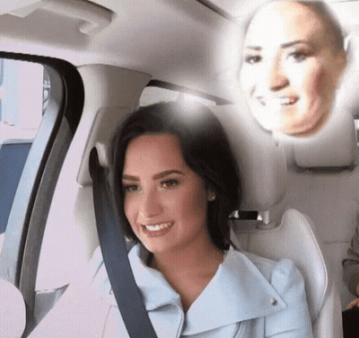 A Woman In A Car With A Reflection Of Her Face On The Back Seat GIF