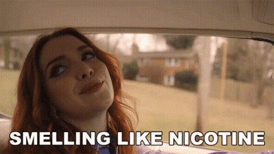 A Woman In A Car With The Words Smelling Like Nicotine GIF