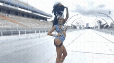 A Woman In A Carnival Costume Is Dancing On The Street GIF