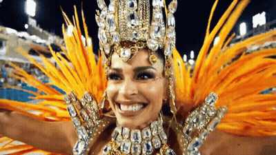 A Woman In A Carnival Costume With Feathers And Rhinestones Is Smiling . GIF