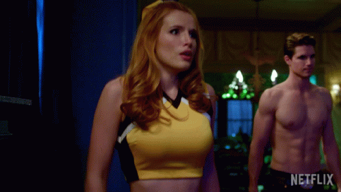 A Woman In A Cheerleader Outfit Stands Next To A Shirtless Man With A Netflix Logo In The Corner GIF