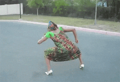A Woman In A Colorful Dress Is Dancing On A Road GIF