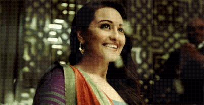 A Woman In A Colorful Dress Is Smiling In Front Of A Man In A Suit . GIF