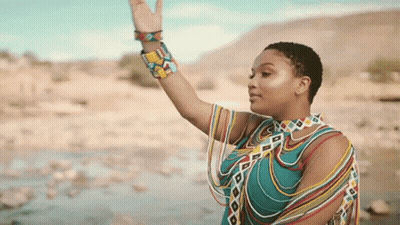 A Woman In A Colorful Dress Is Waving Her Hand GIF