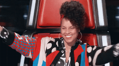 A Woman In A Colorful Jacket Is Sitting In A Chair With Her Arms Outstretched And Smiling . GIF