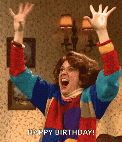 A Woman In A Colorful Sweater Is Celebrating Her Birthday With Her Hands In The Air . GIF