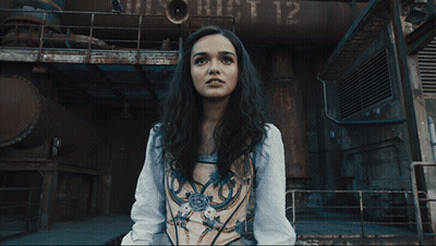 A Woman In A Corset Is Standing In Front Of A Building With The Number 12 On It GIF