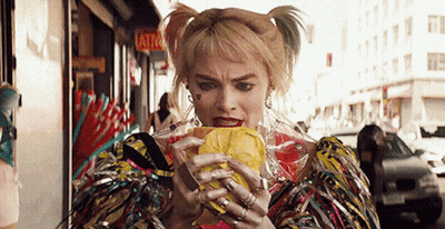 A Woman In A Costume Is Eating A Sandwich On The Street . GIF