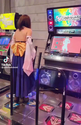 A Woman In A Costume Is Playing Dance Dance Revolution GIF