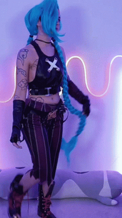 A Woman In A Costume With Blue Hair And A Cross On Her Shirt GIF