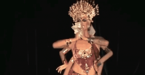 A Woman In A Costume With Many Arms And A Crown Is Dancing On A Stage . GIF