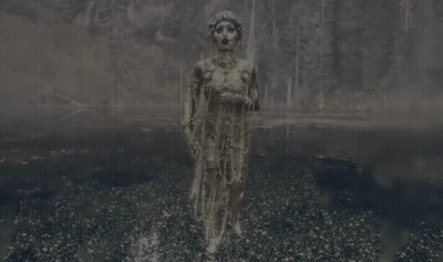 A Woman In A Costume With Pearls Hanging From Her Neck GIF