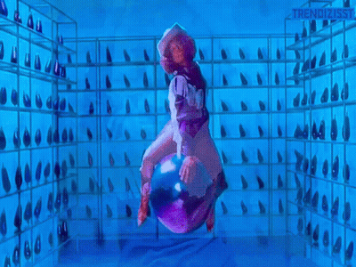 A Woman In A Cowboy Hat Is Riding A Purple Object In A Room With A Lot Of Shoes On Shelves . GIF