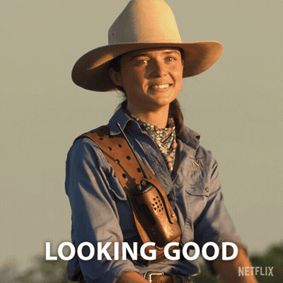 A Woman In A Cowboy Hat Is Smiling With The Words Looking Good Below Her GIF