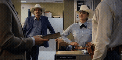 A Woman In A Cowboy Hat Stands In Front Of A Desk With The Name Mark Ramirez Written On It GIF